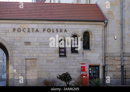 Posen, Polen - 8. April 2025: Steinfassade des Poczta Polska-Gebäudes mit Bogenfenstern und rotem Briefkasten mit traditionellem Architekturstil Stockfoto