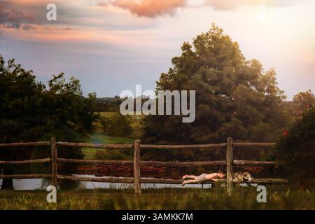 Junge und Katze sitzen im Sommer auf Zaunpfosten Stockfoto