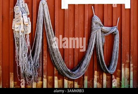Fischernetze hängen zum Trocknen an einer schwedischen roten Wand. Stockfoto
