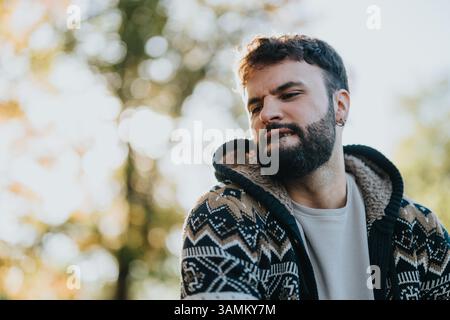 Mann in gemustertem Pullover, der nachdenkliche Emotionen im Freien ausdrückt Stockfoto