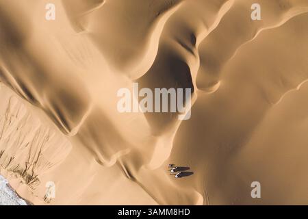 Aus der Vogelperspektive von zwei Geländejeeps, die auf den Sanddünen entlang der Küste in der Nähe von Walvis Bay, Namibia, geparkt sind. Stockfoto