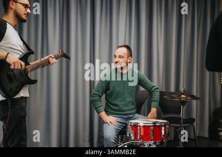 Musiker üben gemeinsam in einem Studio mit Gitarre und Schlagzeug Stockfoto