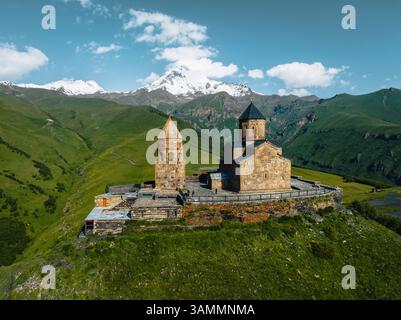 Blick aus der Vogelperspektive auf die gergeti trinity Kirche, umgeben von majestätischen Bergen und ruhiger Landschaft, Stepantsminda, Georgia. Stockfoto