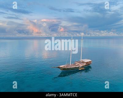 Blick aus der Vogelperspektive auf das wunderschöne Segelboot auf dem blauen Ozean mit einer atemberaubenden Küste, Amingiri, Male Atoll, Malediven. Stockfoto
