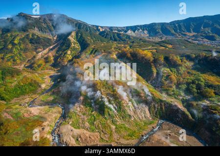 Blick aus der Vogelperspektive auf das atemberaubende Tal der Geysire, umgeben von majestätischen Bergen und Dampf, Kamtschatka, Russland. Stockfoto