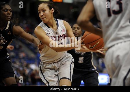 19. Februar 2014 - Hartford, CT, USA - die Connecticut Huskies-Wärterin Saniya Chong (12) fährt am Mittwoch, den 19. Februar 2014, in die Lane gegen Stephanie Taylor (42) der Central Florida Knights Stürmer und serviert dann in der zweiten Halbzeit vor einem Teamkollegen im XL Center in Hartford, USA. Huskies gewann 83:35. (Kreditbild: © John Woike/MCT/ZUMAPRESS.com) Stockfoto