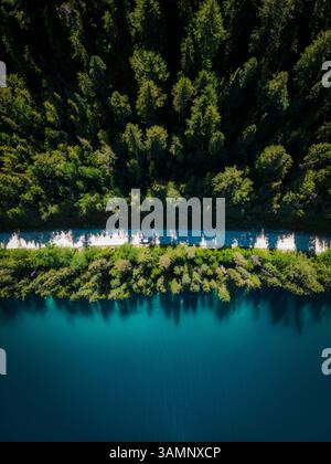 Blick aus der Vogelperspektive auf den ruhigen Johnson Lake mit türkisfarbenem Wasser, umgeben von üppigem Wald und einer gewundenen Straße, Louis Creek, British Columbia, Kanada. Stockfoto