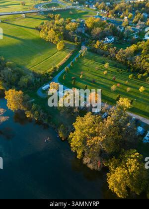 Blick aus der Vogelperspektive auf das lebhafte Herbstlaub und den ruhigen Fluss, der sich durch die malerische Landschaft mit Häusern und Feldern schlängelt, Riverton Junction, Virginia, Uni Stockfoto