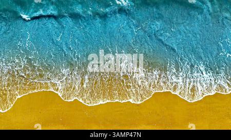 Blick auf die Meereswellen am Sandy Beach aus der Vogelperspektive. Blick von oben auf türkisfarbene Wellen des Ozeans, die sanft auf einen goldenen Sandstrand krachen, wodurch ein lebendiges und lebendiges Leben entsteht Stockfoto