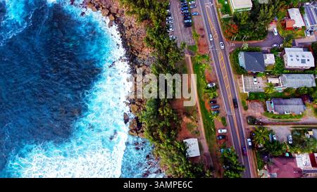 Luftaufnahme der Küstenstraße in Hawaii. Ein atemberaubender Blick aus der Luft auf eine Küstenstraße in Hawaii, bei der Wellen gegen felsige Küsten neben einem brechen Stockfoto