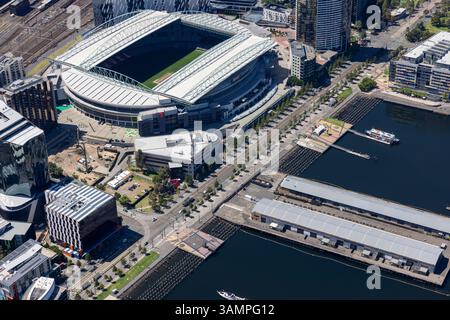 Blick aus der Vogelperspektive auf das pulsierende Stadion und die Uferpromenade mit modernen Gebäuden und Hafen, Docklands, Melbourne, Australien. Stockfoto