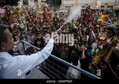 19. Januar 2014 – Manila, Philippinen – philippinische Katholiken erheben ihre Santo Nino Statuen, während sie während des Festes von Santo Nino in einer Kirche im armen Stadtteil Tondo mit Weihwasser besprüht werden. Das Festival wird jeden dritten Sonntag im Januar gefeiert, bei dem das Jesuskind, besser bekannt als „Santo Nino“, an philippinische Katholiken geehrt wird. (Bild: © Ezra Acayan/ZUMAPRESS.com) Stockfoto