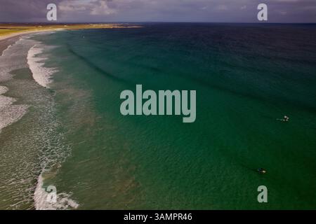 Aus der Vogelperspektive surfen am ruhigen Sandstrand mit wunderschönen Meereswellen, Crossapol, Isle of Tiree, Schottland. Stockfoto
