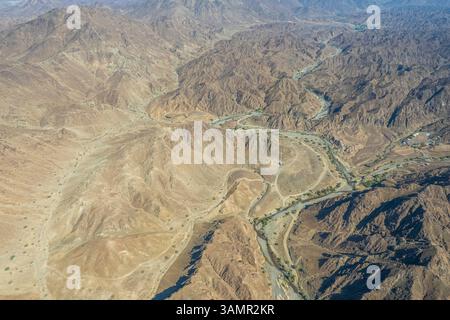 Blick aus der Vogelperspektive auf Wadi Shawqa, einen Canyon zwischen den felsigen Hügeln in Ras al-Khaimah, Vereinigte Arabische Emirate. Stockfoto