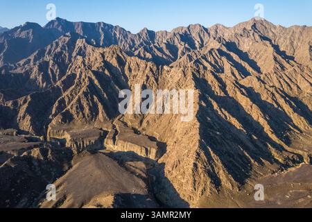 Aus der Vogelperspektive eines Canyons zwischen den felsigen und trockenen Bergen in der Wüste im Bundesstaat Ajman, Vereinigte Arabische Emirate. Stockfoto