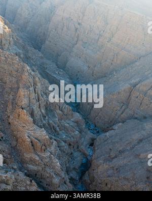 Blick aus der Vogelperspektive auf Wadi Shawqa, einen Canyon zwischen den felsigen Hügeln in Ras al-Khaimah, Vereinigte Arabische Emirate. Stockfoto