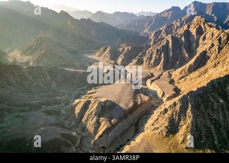 Aus der Vogelperspektive eines Canyons zwischen den felsigen und trockenen Bergen in der Wüste im Bundesstaat Ajman, Vereinigte Arabische Emirate. Stockfoto
