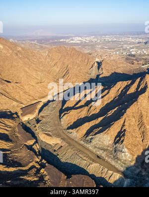 Aus der Vogelperspektive eines Canyons zwischen den felsigen und trockenen Bergen in der Wüste im Bundesstaat Ajman, Vereinigte Arabische Emirate. Stockfoto