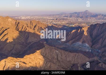 Aus der Vogelperspektive eines Canyons zwischen den felsigen und trockenen Bergen in der Wüste im Bundesstaat Ajman, Vereinigte Arabische Emirate. Stockfoto