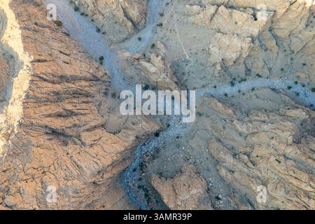 Blick aus der Vogelperspektive auf Wadi Shawqa, einen Canyon zwischen den felsigen Hügeln in Ras al-Khaimah, Vereinigte Arabische Emirate. Stockfoto