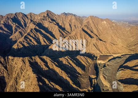 Aus der Vogelperspektive eines Canyons zwischen den felsigen und trockenen Bergen in der Wüste im Bundesstaat Ajman, Vereinigte Arabische Emirate. Stockfoto