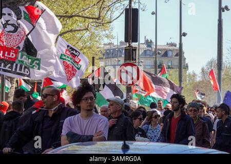 Demonstranten marschieren mit Fahnen und Bannern während einer propalästinensischen Kundgebung/Demonstration/Protest in Paris, wobei der Schwerpunkt auf einer Flagge mit arabischem Text liegt Stockfoto