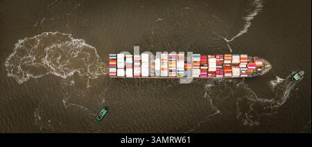 Ein Blick von oben nach unten auf Schlepper, die ein Containerschiff aus dem Hafen ziehen, bereit für die Abfahrt Stockfoto