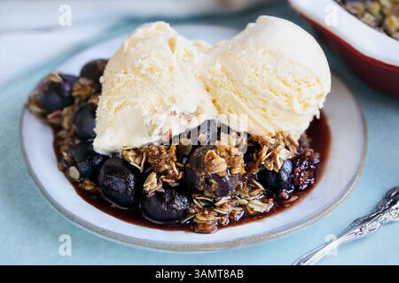 Hausgemachte Kirschknusprig serviert mit französischem Vanilleeis. Selektiver Fokus mit unscharfem Hintergrund. Stockfoto