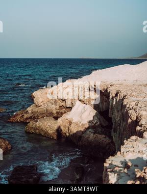 Am Delisha Beach, Socotra, prallen Wellen gegen die felsige Küste unter den Sanddünen. Stockfoto