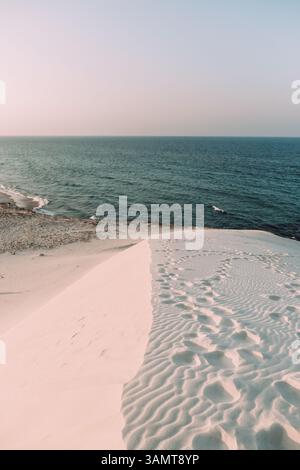 Fußspuren führen über windgeformte Sanddünen am Delisha Beach, Socotra. Stockfoto