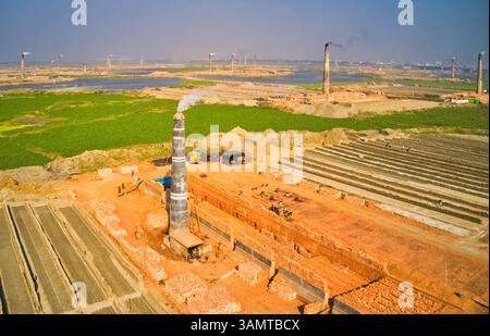 Aus der Vogelperspektive mehrerer Schornsteine aus einer Ziegelfabrik entlang des Karnatali-Zuflusses in der Nähe von Savar City, Dhaka, Bangladesch. Stockfoto