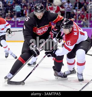 14. Februar 2014 – Sochi, RUS – Kanada-Stürmer Ryan Getzlaf (15) und Österreich-Stürmer Michael Raffl (12) kämpfen um den Puck während der ersten Periode eines Männer-Hockeyspiels bei den Olympischen Winterspielen in Sotschi, Russland, Freitag, 14. Februar 2014. Kanada besiegte Österreich mit 6:0. (Bild: © Harry E. Walker/MCT/ZUMAPRESS.com) Stockfoto