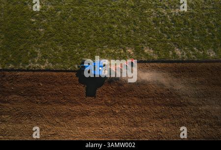 Aus der Vogelperspektive eines Traktors, der vor der Aussaat in Lomellina, Potal, Italien durch Bodenbearbeitung mit einem maschinellen Pflug ein Feld pflügt. Stockfoto