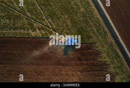 Aus der Vogelperspektive eines Traktors, der vor der Aussaat in Lomellina, Potal, Italien durch Bodenbearbeitung mit einem maschinellen Pflug ein Feld pflügt. Stockfoto