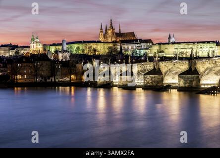 Karlsbrücke mit Blick nach Westen in Richtung der Burg Prag zur blauen Stunde mit reflektierenden Lichtern Stockfoto