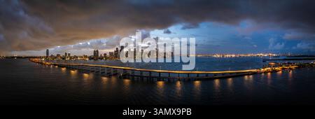 Blick aus der Vogelperspektive auf die Skyline der Innenstadt von miami in der Abenddämmerung mit dem rickenbacker Causeway und den beleuchteten Hochhäusern, virginia Key, usa. Stockfoto