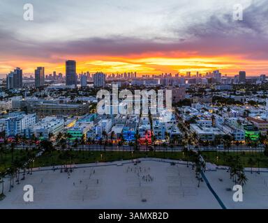 Blick aus der Vogelperspektive auf die farbenfrohe Skyline und den Strand mit Palmen in der Dämmerung, Ocean Drive, South Beach, USA. Stockfoto