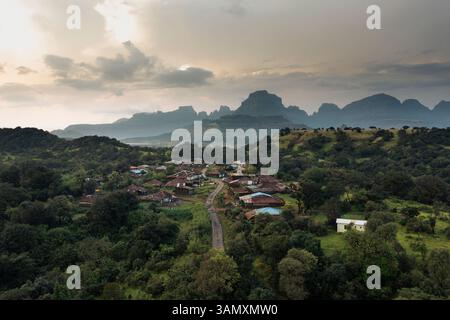 Blick aus der Vogelperspektive auf das friedliche Dorf eingebettet zwischen Bergen und Bäumen, Nashik Viertel, Maharashtra, Indien. Stockfoto