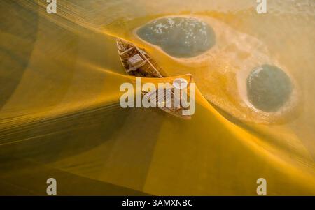Blick aus der Vogelperspektive auf das traditionelle Fischerboot mit gelben Netzen im Wasser, Hoi an, Provinz Quang Nam, Vietnam. Stockfoto