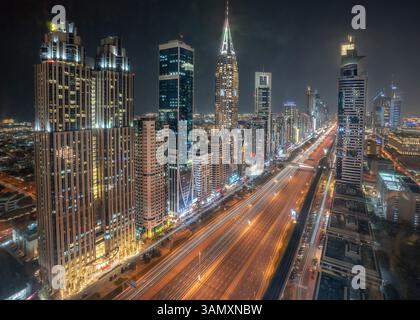 Aus der Vogelperspektive die pulsierende Nachtlandschaft mit beleuchteten Gebäuden entlang der Sheikh Zayed Road, Dubai, Vereinigte Arabische Emirate. Stockfoto