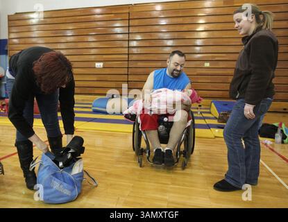 17. Januar 2014 - Tallmadge, OH, USA - Akron Rhinos Quad Rugby-Teammitglied Adam Sweeney, Mitte, hält seine 15 Monate alte Tochter Dahlia Sweeney, nachdem er am 17. Januar 2014 im Weaver Learning Center in Tallmadge, Ohio, geübt wurde. Auf der linken Seite ist Perri Sweney Ehefrau und auf der rechten Seite Coach Megan Haas. (Bild: © Phil Masturzo/MCT/ZUMAPRESS.com) Stockfoto