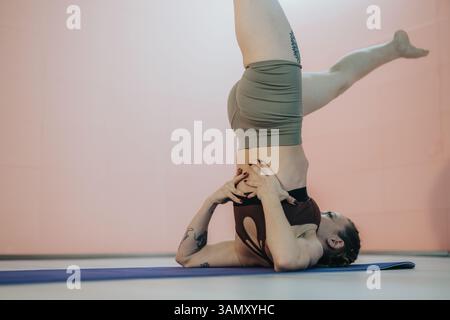 Frau übt Kopfstand-Yoga-Pose auf der Matte in ruhiger Indoor-Umgebung Stockfoto