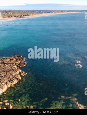 Aus der Vogelperspektive auf die felsige Küste mit Surfern und Paddelboardern, Cornwall, Godrevy Lighthouse, Großbritannien. Stockfoto