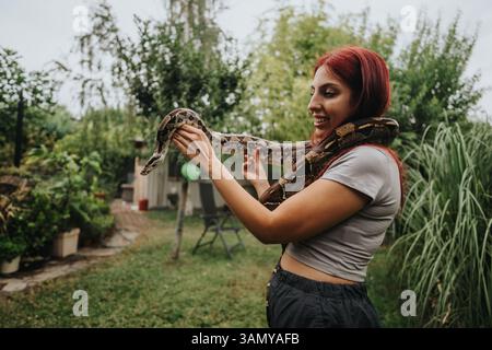 Ein Mädchen hält eine große Schlange in einem Garten im Freien Stockfoto