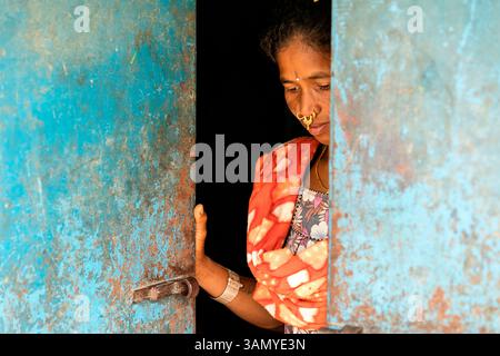 Eine Frau, die mit Nasenringen und Schmuck dekoriert ist, steht an den Türen ihres Hauses in einem kleinen Dorf in orissa, indien Stockfoto