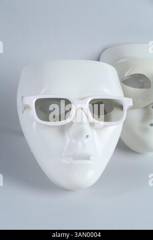 Theatermasken aus Plastik mit Sonnenbrille auf hellgrauem Hintergrund Stockfoto
