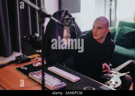 Ein Musiker konzentriert sich auf die Musikproduktion in einem Heimstudio mit Gitarre und professioneller Audioausrüstung. Stockfoto