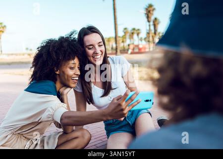 Zwei glückliche Freundinnen, die draußen ein Selfie mit Smartphone machen Stockfoto
