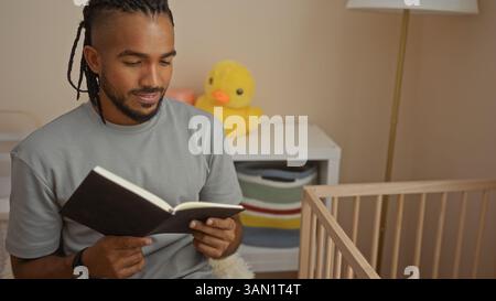 Junger Mann mit Zöpfen, der ein Buch in einem gemütlichen Schlafzimmer mit Holzbett und Plüschtier in der Nähe liest, bietet eine ruhige und friedliche Innenatmosphäre. Stockfoto