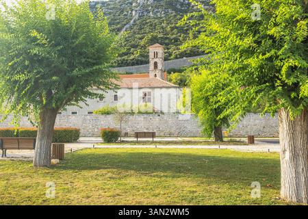 Ston, historische Stadt auf der Halbinsel Peljesac in Kroatien, Europa. Idyllischer Blick auf einen Park mit üppigen Bäumen und ein historisches Gebäude mit einem Glockenturm im Stockfoto